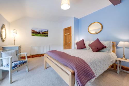 a bedroom with a bed and a chair and a mirror at Gwel y Bryn in Corris