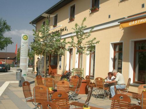 two people sitting in chairs outside of a building at Gasthof Strausberg Nord in Strausberg