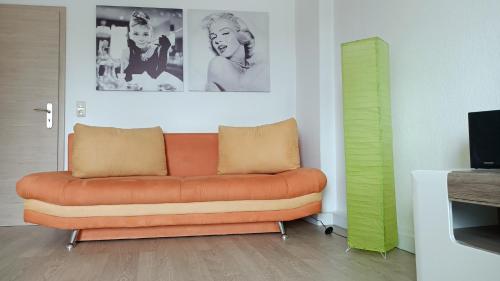 ein orangefarbenes Sofa im Wohnzimmer mit einem TV in der Unterkunft Gäste und Ferienwohnung Gläser Zwickau in Zwickau