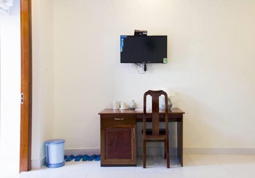 una scrivania con sedia e una TV a parete di Nhà nghỉ Linh Quân a Vung Tau