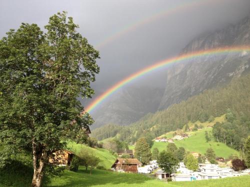 a rainbow over a village with a mountain at Locherboden in Grindelwald