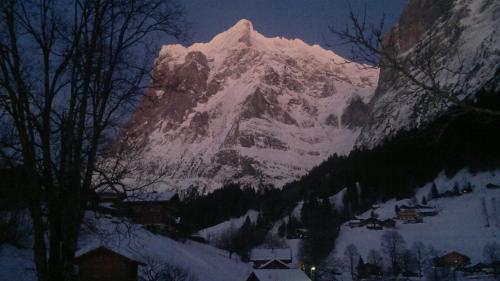 a snow covered mountain at night with a village in front at Locherboden in Grindelwald
