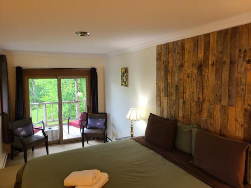 1 dormitorio con 1 cama con pared de madera en Le Lodge du lac, en Saint-Faustin