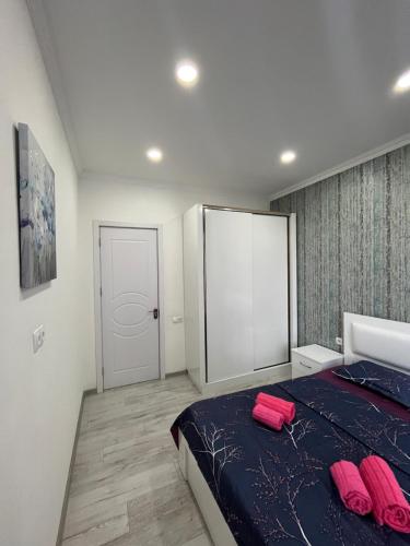 a bedroom with a bed with two pink pillows on it at Kobi Apartments in Tbilisi City