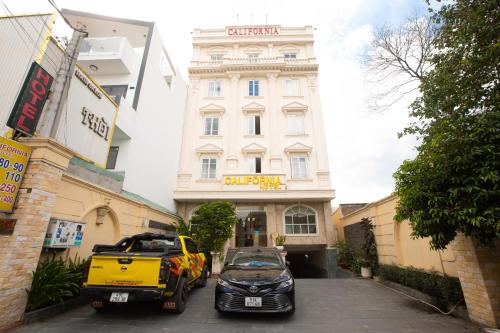 dois carros estacionados em frente a um edifício em California Hotel em Ho Chi Minh