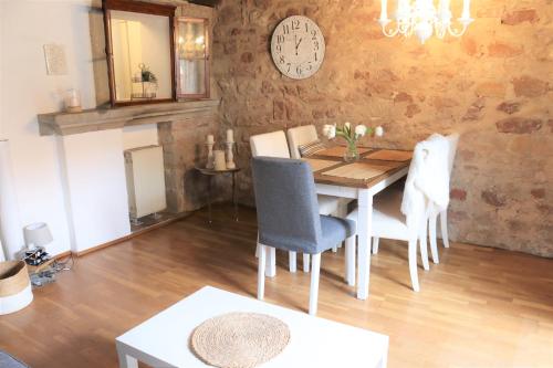 ein Esszimmer mit einem Tisch, Stühlen und einer Uhr in der Unterkunft Ferienwohnung, Charmantes Bauernhaus, Ferienhaus in Saarlouis