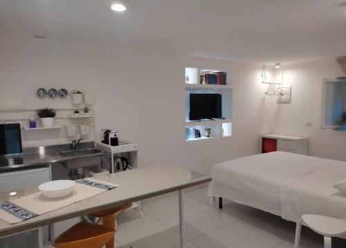 a white room with a bed and a kitchen at Le Petit Nid d'Assise in Bastia Umbra