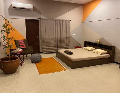 a bedroom with a bed and a chair and a plant at Costa Verde Luxury Seafront Villa in Chennai