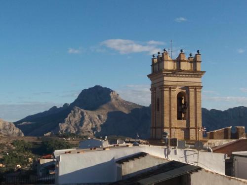 a building with a bell tower with mountains in the background at Can Perles casa rural in Tárbena