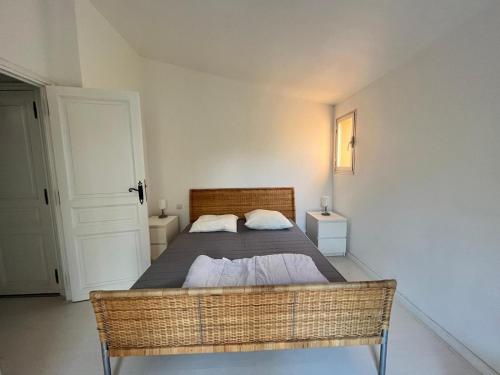 - une chambre avec un lit et un cadre de lit en osier dans l'établissement Les Hauts de Bonporteau - nr 29, à Cavalaire-sur-Mer