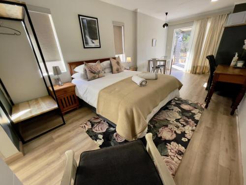 a bedroom with a bed and a table and a desk at Meander Stay Clarens in Clarens