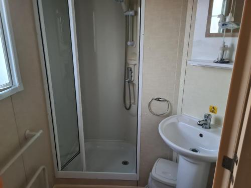 a bathroom with a shower and a toilet and a sink at Chris’s caravan in Abergele