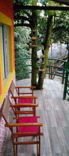 a group of chairs with pink cushions sitting on a porch at montecarlos hotel in Ibagué