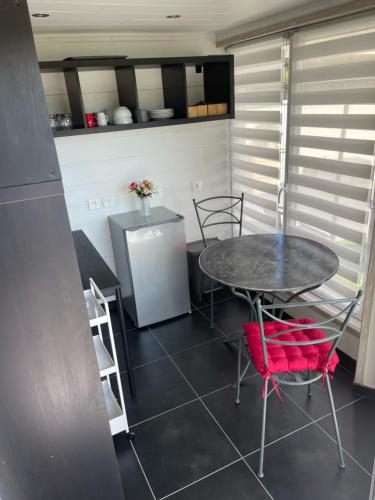 une cuisine avec une table, des chaises et un réfrigérateur dans l'établissement relais des tourterelles, à La Neuville-aux-Joûtes