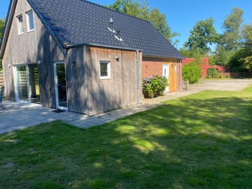 a barn with a grass yard next to a house at Vakantiehuisje drenthe gasselterveld in Gasselte
