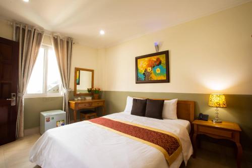 a bedroom with a large white bed and a window at Atana Hotel in Ho Chi Minh City