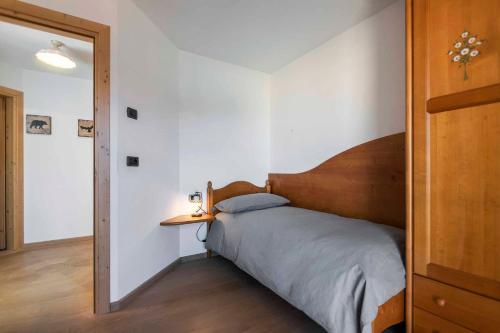 a bedroom with a bed with a wooden headboard at Casa Rododendro - Cavalese Dolomites in Cavalese
