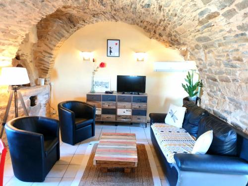 Elle comprend un salon doté d'un mobilier en cuir et d'un mur en pierre. dans l'établissement Gîte l'Echappée belle, à Castelnau-Pégayrols