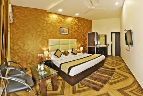 a bedroom with a bed and a table and a tv at Hotel Amritsar Inn in Amritsar