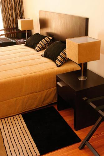 a bedroom with a large bed with a table and a bed sidx sidx at Hotel Quinta Progresso in Macieira de Cambra