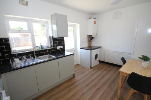 a kitchen with white cabinets and a table and a tableablish at The Heathrow House in Cranford