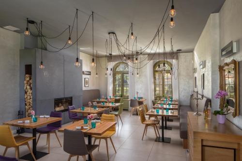 un restaurante con mesas y sillas y una lámpara de araña en Hercegasszony Birtok en Mezőtúr