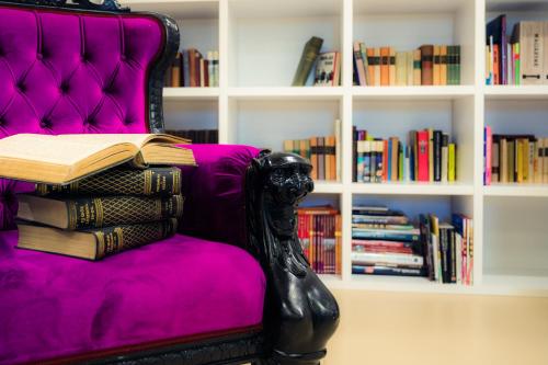 a pile of books sitting on a purple couch at Hercegasszony Birtok in Mezőtúr