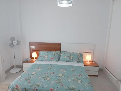 a bedroom with a bed with a blue comforter and two lamps at APARTAMENTO SAN JUAN in Sanlúcar de Barrameda