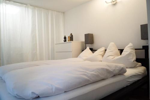 białe łóżko z białą pościelą i poduszkami w obiekcie Wohlfühlen am Großen Goitzschesee inkl. Netflix w mieście Holzweißig