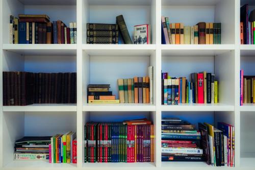 a white book shelf filled with lots of books at Hercegasszony Birtok in Mezőtúr