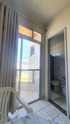 a bathroom with a toilet and a sliding glass door at POUSADA POLONINI - Localização ótima in Piúma