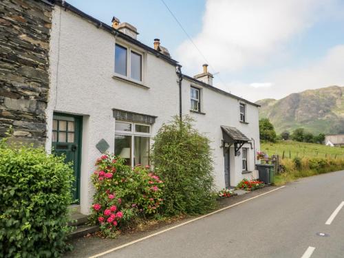 a white house with flowers on the side of a street at 2 Gateside Cottages in Coniston