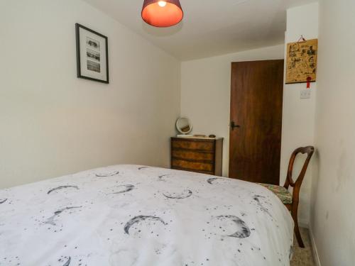 a bedroom with a bed with a white comforter at 2 Gateside Cottages in Coniston