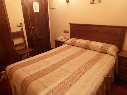 a bedroom with a large bed with a wooden headboard at Hostal Virgen de la Encina in Ponferrada