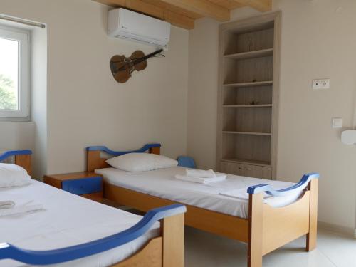two beds in a room with a guitar on the wall at TH Studio in Myrina