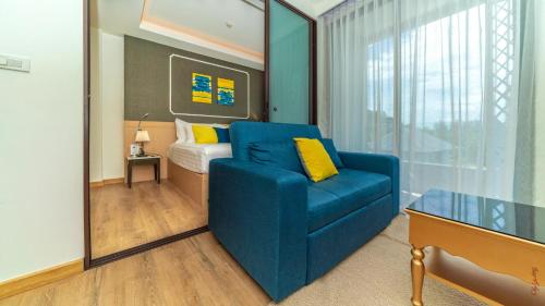 a living room with a blue couch and a bed at The Aristo-2-903 in Ban Lum Fuang