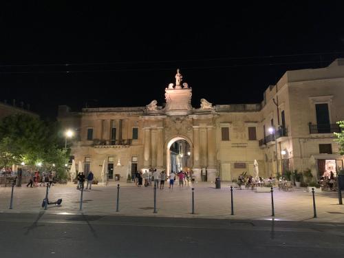 un grande edificio con persone che camminano davanti di notte di Guest House Mela a Lecce
