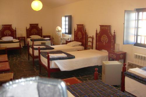 LavreにあるCasa da Malta do Monte dos Arneirosのベッド3台と椅子が備わる客室で、