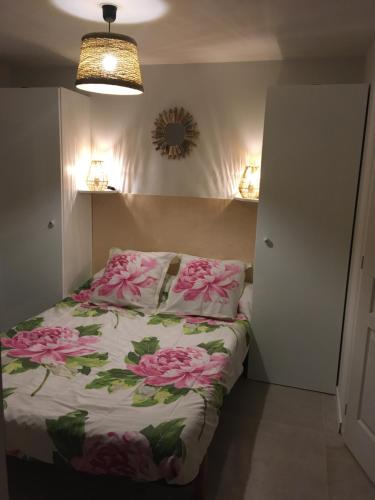 Un dormitorio con una cama con flores rosas. en Le Patio du bourg - Studio entre lac et océan, en Biscarrosse