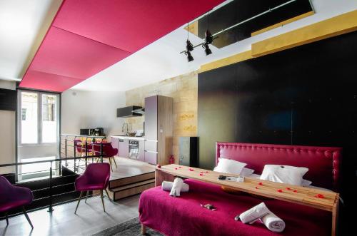 a bedroom with a red bed and a kitchen at Mieuxqualhotel jacuzzi privatif Love room in Bordeaux