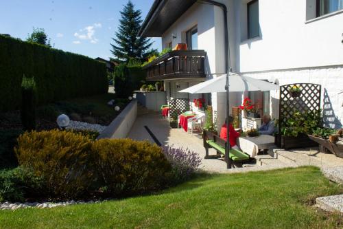 a garden with a person sitting on a bench and an umbrella at Garden Apartments Janša in Radovljica