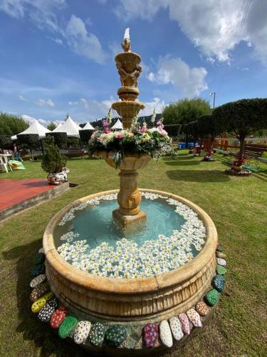 a fountain with flowers in the middle of a park at El Nogal finca-hotel in Firavitoba
