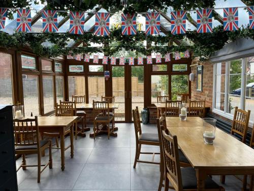 un ristorante con tavoli e sedie in legno e bandiere di The Six Bells a Newbury