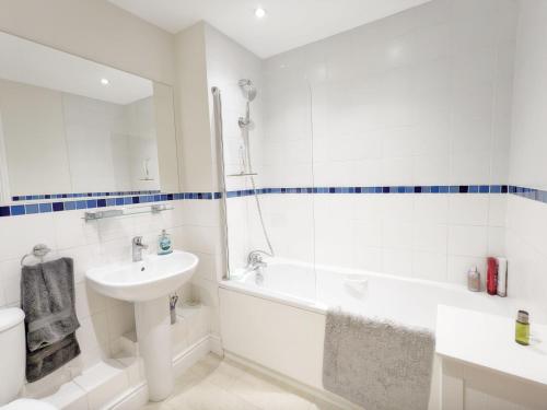 a white bathroom with a sink and a tub and a toilet at Pears Grove - Southbourne in Emsworth