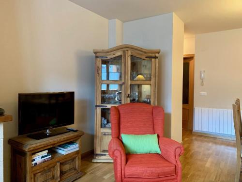 een woonkamer met een rode stoel en een tv bij BPIRINEOS-Albares in Benasque