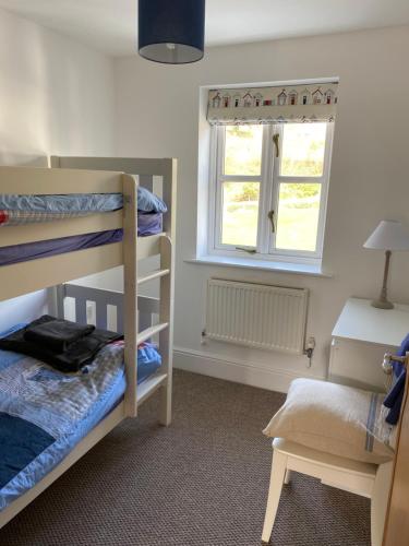 a bedroom with two bunk beds and a window at Waters Reach in Abersoch