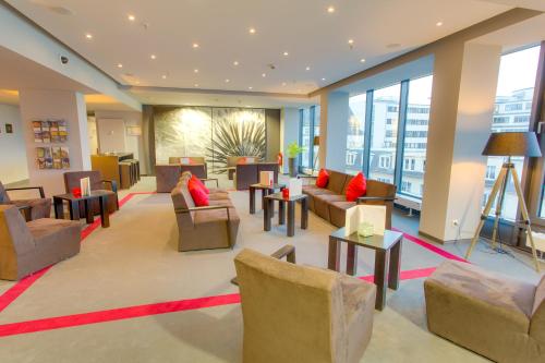 a lobby with couches and tables and windows at Biendo Hotel in Chemnitz