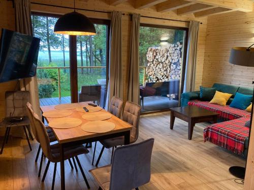 a dining room with a table and a living room at Ostoja Leśniewo in Srokowo