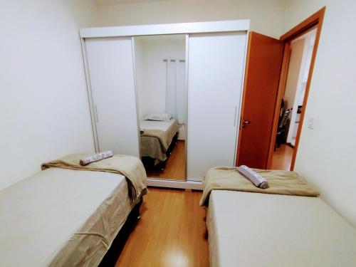 a small room with two beds and a mirror at APTO, 2 quartos, confortável e bem localizado in Palmas