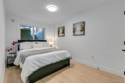 a white bedroom with a bed and two pictures on the wall at Guest suite in South Surrey in Surrey